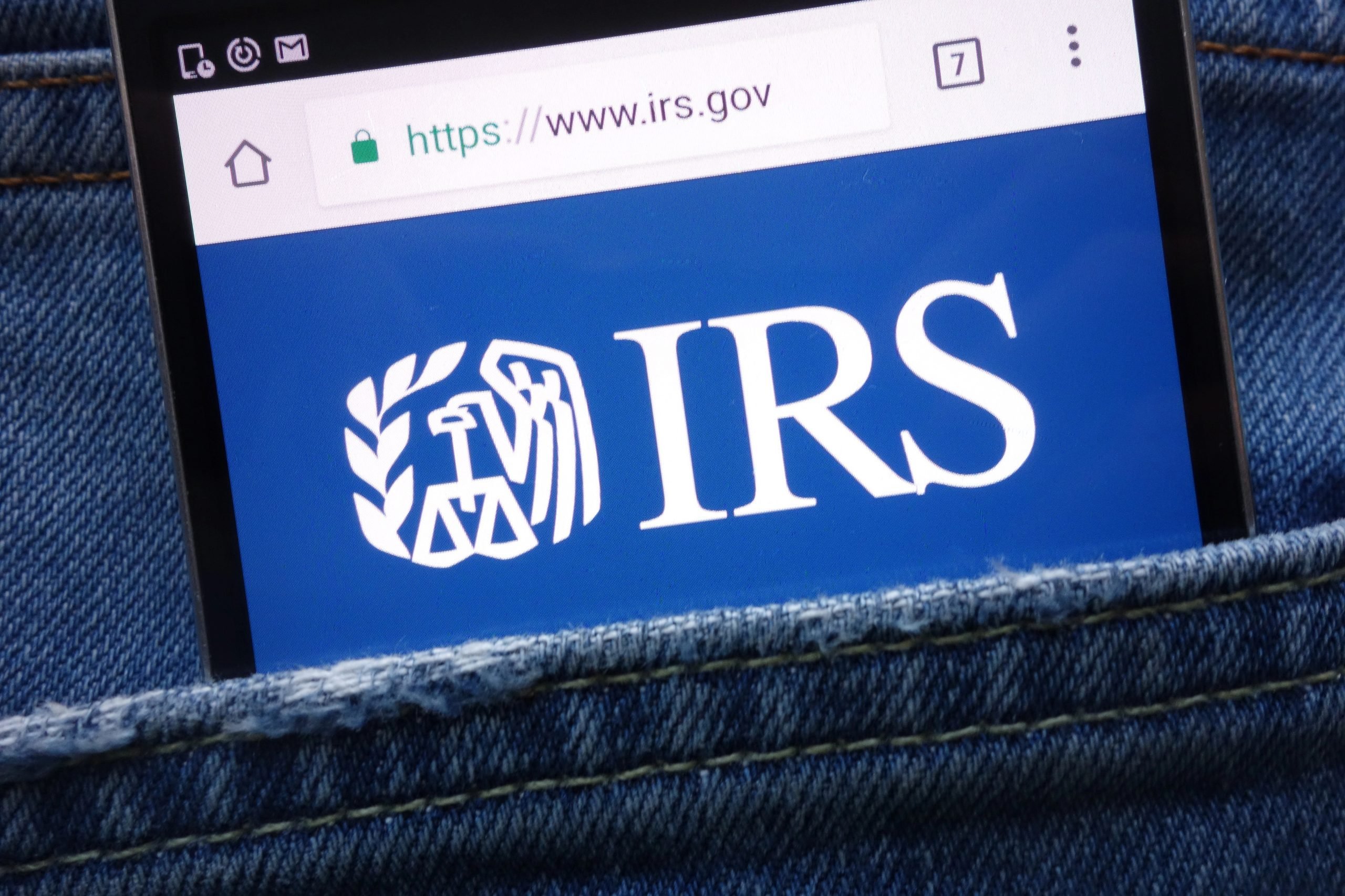 IRS (Internal Revenue Service) website displayed on smartphone hidden in jeans pocket