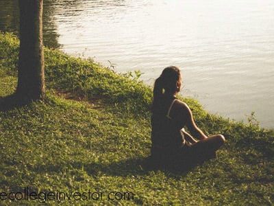 A woman doing yoga in a park by a lake, representing the free hobbies that you can do.