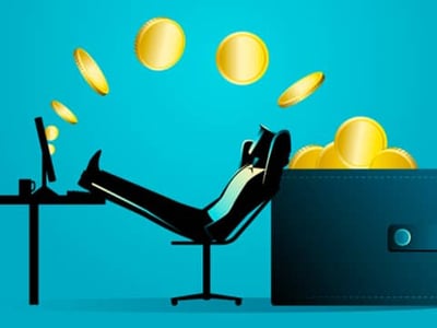 This image depicts a stylized illustration on a light blue background, visually representing the concept of passive income and high-yield online savings. A minimalist figure, rendered in black silhouette, is seated comfortably in an office chair with their feet propped up on a desk. On the desk, a laptop is open, suggesting online activity or banking. To the right of the figure, a large, dark blue wallet or ledger stands upright, overflowing with gold coins and paper money, symbolizing substantial savings and financial growth. Above the figure's head, more gold coins appear to be raining down, reinforcing the idea of money being accumulated effortlessly. The red text overlay, though partially obscured, includes words like "REVIEW:" and "POPULAR ONLINE SAVINGS," directly relating to the article's focus on Bread Savings (formerly Comenity Direct) and its high-yield online savings account and CD products. The overall image conveys financial freedom, smart banking choices, and the benefits of online savings accounts with competitive APY rates.