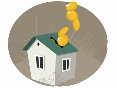 An illustration depicts a small, white house with a dark green roof, centered within a grey circular background that includes subtle hints of tall, dry grass on the right side. Several shining gold coins are shown falling from the top of the image, with some landing directly into a slot on the house's roof, symbolizing an investment into the home. The artwork represents the concept of tapping into home equity, as discussed in the accompanying article about Hometap, a fintech company offering an alternative to traditional home equity loans. The bottom left of the image features "THE COLLEGE INVESTOR" in white, bold, sans-serif text, identifying the source of this content.