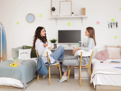 Female students talking at table in dorm room | Photo Credit: zereznly