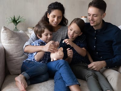 Caring young happy couple parents teaching small children son daughter saving money for future.