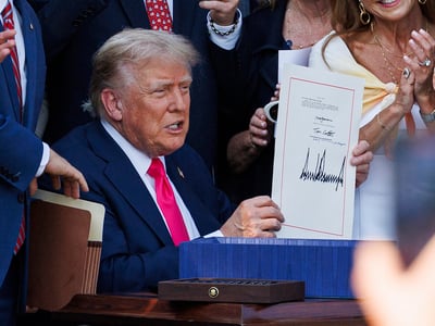 President Donald Trump signs his tax and spending bill into law during a 4th of July celebration with military families on the South Lawn of the White House in Washington DC, on Friday July 4, 2025. The 'One Big Beautiful Bill Act' cuts government spending and taxes and adds work requirements to medicaid, passed through both chambers of Congress in party-line votes. (Photo by Aaron Schwartz/Sipa USA)(Sipa via AP Images)