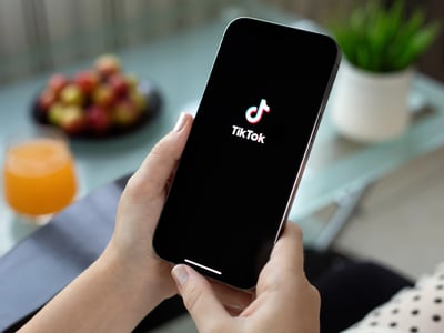Woman holding Apple iPhone 15 Pro Max with streaming service media and video TikTok on the screen | Photo by prykhodov