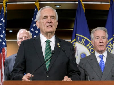 U.S. Representative Lloyd Doggett speaks at a podium during a press conference, flanked by colleagues and American flags. The image captures the Congressman introducing the Health Savings Account Consumer Protection Act, a proposal aimed at tightening HSA rules to address tax avoidance by high-income households and implement stricter fee transparency. (AP Photo/Rod Lamkey, Jr.)