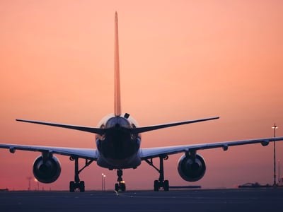 Passenger jet plane preparing for takeoff on an airport runway against a vibrant sunset sky. This image symbolizes the journey of international graduate students pursuing education abroad, highlighting the complex financial planning, visa uncertainties, and funding decisions they must navigate before "taking off" on their academic careers.