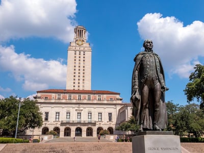 The George Washington statue at the University of Texas at Austin stands prominently in front of the iconic tower. This image represents the broader national conversation on higher education funding and policy, specifically referencing Texas colleges losing millions in federal Hispanic-Serving Institution (HSI) grants, a major headline in this week's college and money news.