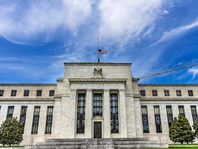 Front view of the Federal Reserve headquarters building in Washington, D.C., under a bright blue sky. This image represents the recent report from the Federal Reserve Bank of Philadelphia analyzing the impact of upcoming 2026 graduate student loan caps, which could leave nearly one in three borrowers facing a funding gap. Source: The College Investor