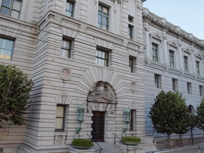 Exterior view of a grand, historic federal courthouse featuring classical stone architecture, rusticated walls, and an ornate arched entrance flanked by decorative green lantern fixtures. This stately building represents the Ninth Circuit Court of Appeals, the judicial battleground where the Education Department is currently arguing its motion to delay the Sweet v. McMahon borrower defense settlement—a critical legal decision that could impact up to $12 billion in debt relief for defrauded student loan borrowers. Source: The College Investor