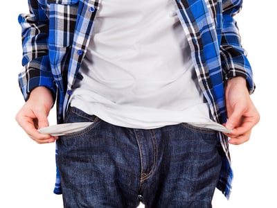 Man in Jeans shows the Empty Pockets Closeup on the White Background reflects the fact that most college dropouts leave school due to financial issues.