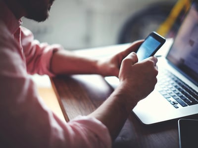 Side view shot of a man's hands using smart phone in interior, rear view of business man hands busy using cell phone at office desk, young male student texting on phone sitting at wooden table