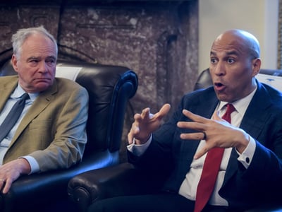 Sen. Tim Kaine, D-Va., left, listens as Sen. Cory Booker, D-N.J., speaks during a press briefing on the Iran war powers resolution at the Capitol, Monday, March 9, 2026, in Washington. (AP Photo/Rod Lamkey, Jr.)