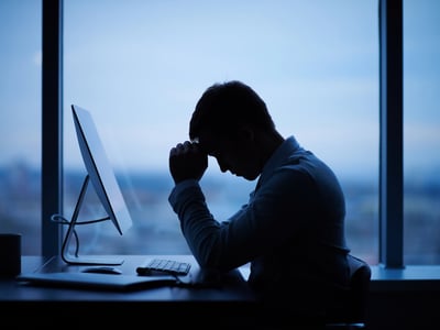 Tired or stressed man at computer due to defaulted student loan debt. Source: The College Investor
