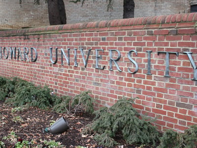 Exterior view of the Howard University sign on a brick wall.
