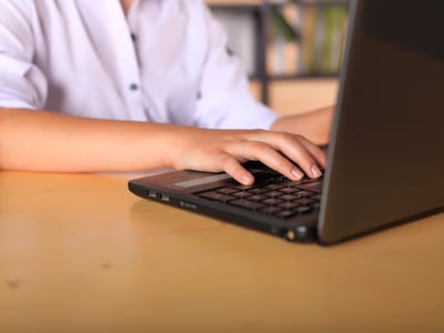 A young girl sits at a computer deciding on college applications and majors in the face of AI.