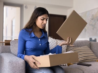 Upset young woman opening box, an analogy to the disgust families face in dealing with the college pricing black box. Source: The College Investor