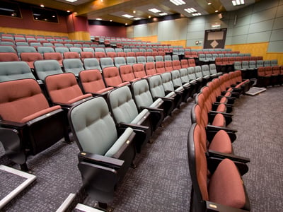 Empty Lecture hall with colorful chairs in a university, reflecting the drop in enrollment due to AI. Source: The College Investor