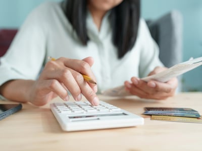 Hand of Asian woman are calculating costs and payments. Source: The College Investor