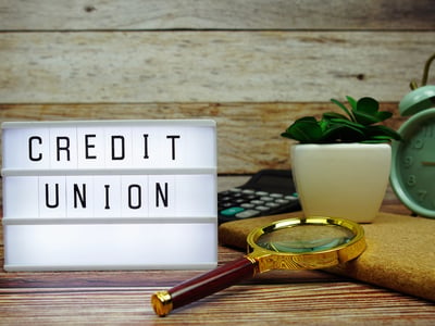 CREDIT UNION letterboard text on LED Lightbox on wooden background. Source: The College Investor