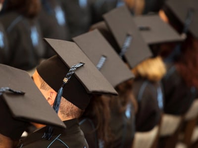 A group of students seated at graduation, highlighting concerns about over educated, under employed.