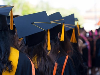 Rear view and soft selective focus of the graduates in the graduation commencement ceremony receiving diploma degree certificate.