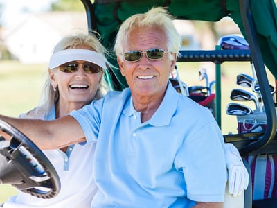 Happy senior man and woman couple together playing golf.