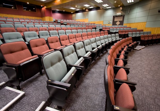Empty Lecture hall with colorful chairs in a university, reflecting the drop in enrollment due to AI. Source: The College Investor