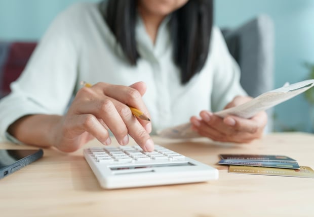 Hand of Asian woman are calculating costs and payments. Source: The College Investor