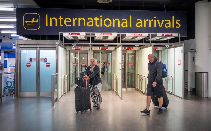 Passengers, International Arrivals stairs, Gatwick Airport, London, UK Male and female passengers with luggage walk through International Arrivals at airport, reflecting the change in international student enrollment at US colleges.