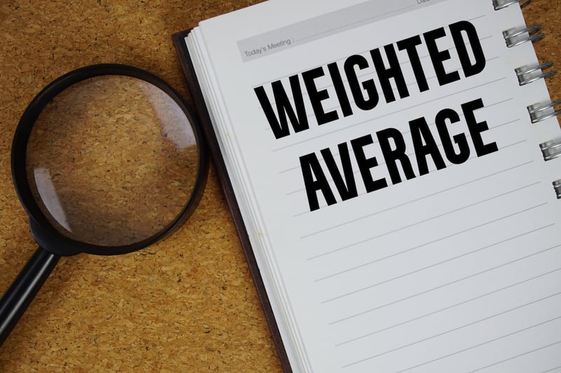 Weighted Average text written on notebook paper with magnifying glass A magnifying glass lies on a corkboard surface next to an open notebook with the bold black text "WEIGHTED AVERAGE" prominently written across the right-hand page, which features horizontal college-ruled lines. The magnifying glass, with a black handle, is positioned on the left side, slightly overlapping the notebook, and its lens reflects a hint of light. The warm, textured corkboard provides a stark contrast to the crisp white notebook paper, emphasizing the central topic of "weighted average" in the context of financial calculations, specifically the PSLF weighted average rule for federal loan consolidation mentioned in the accompanying article. This visual metaphor highlights the importance of scrutinizing and understanding this specific financial concept.