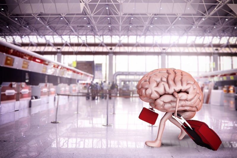 Conceptual 3D illustration of a large human brain with arms and legs, carrying a red suitcase and briefcase while walking through an airport terminal. This visual metaphor represents the potential "brain drain" of graduate students and researchers leaving the United States due to stagnant funding and visa uncertainties, highlighting the risk of losing intellectual capital to competing nations. Source: The College Investor