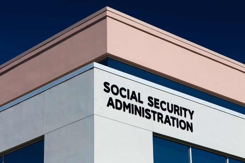 Social Security Administration Exterior view of the Social Security Administration building with bold black signage on the facade. This image represents the structural financial challenges facing the program, including a projected trust fund depletion by 2033, which could result in benefit cuts if Congress does not enact reforms such as adjusting payroll taxes or retirement age. Source: The College Investor
