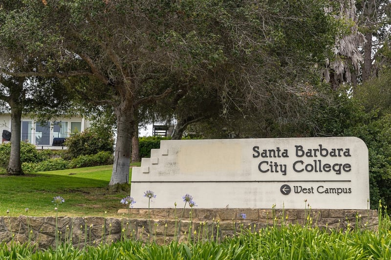 Santa Barbara City College facilities. Closeup, White stone with black name sign set in green garden with tree at entrance to the campus.