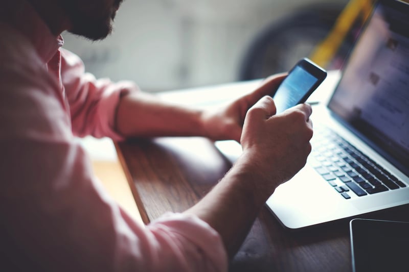 Teen Brokerage Accounts Side view shot of a man's hands using smart phone in interior, rear view of business man hands busy using cell phone at office desk, young male student texting on phone sitting at wooden table
