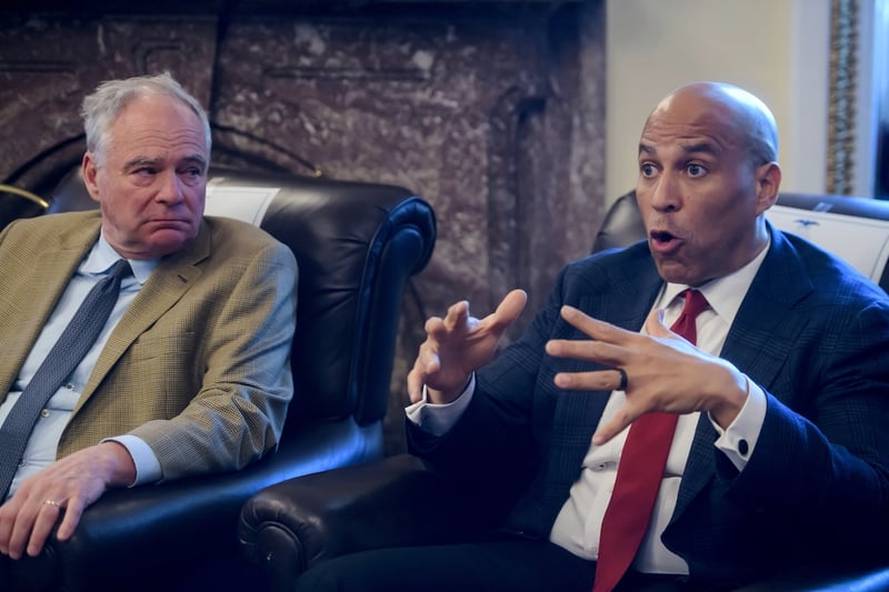 Sen. Tim Kaine, D-Va., left, listens as Sen. Cory Booker, D-N.J., speaks during a press briefing on the Iran war powers resolution at the Capitol, Monday, March 9, 2026, in Washington. (AP Photo/Rod Lamkey, Jr.)