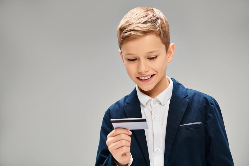 A picture of a schoolage boy holding a credit card, representing financial literacy in America. Source: The College Investor