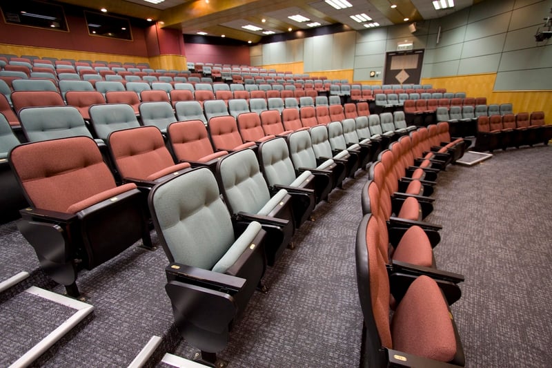Empty Lecture hall with colorful chairs in a university, reflecting the drop in enrollment due to AI. Source: The College Investor