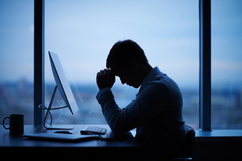 Tired or stressed man at computer due to defaulted student loan debt. Source: The College Investor
