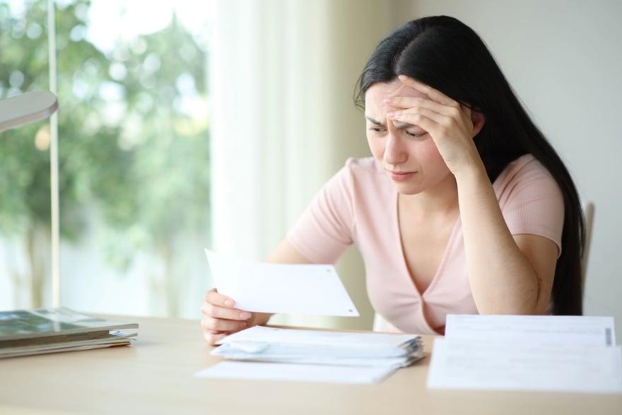 Worried asian woman checking invoice at home Denied A Student Loan | Source: The College Investor