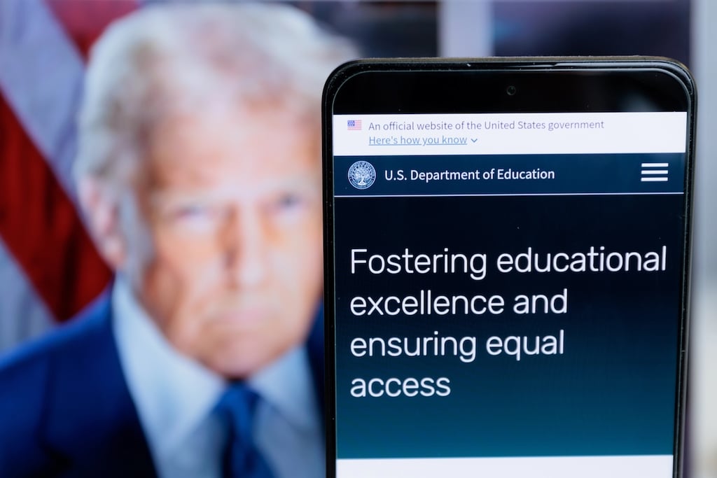 An image of the US Department of Education website saying "Fostering Educational Excellence and Ensuing Equal Access" with an image of President Trump blurred in the background.