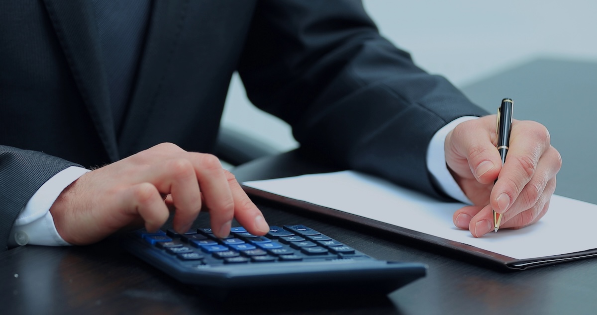 Un homme d'affaires utilise une calculatrice pour effectuer des calculs Taux de refinancement des prêts étudiants | Source : The College Investor