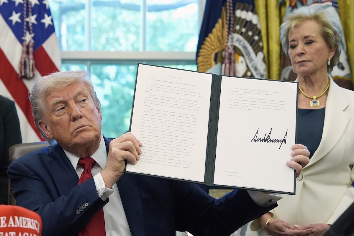 Le président Donald Trump tient un décret signé relatif aux politiques disciplinaires scolaires, tandis que la secrétaire à l'Éducation, Linda McMahon, écoute dans le Bureau ovale de la Maison-Blanche, le mercredi 23 avril 2025, à Washington. (Photo AP/Alex Brandon)
