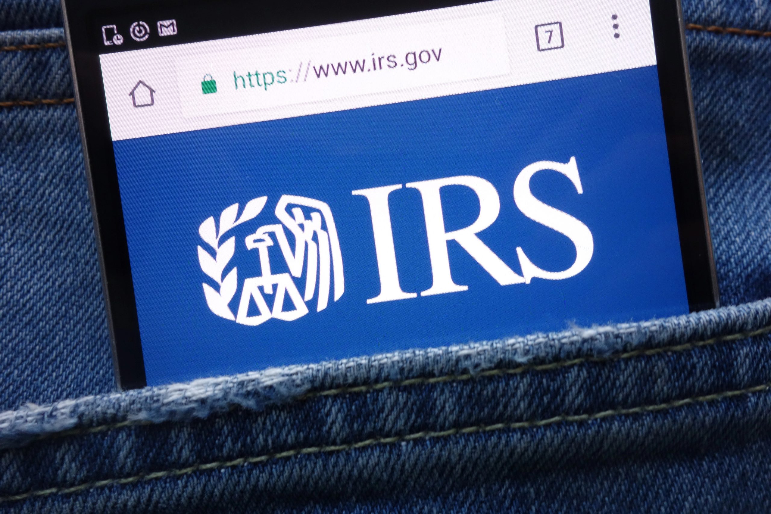 IRS (Internal Revenue Service) website displayed on smartphone hidden in jeans pocket